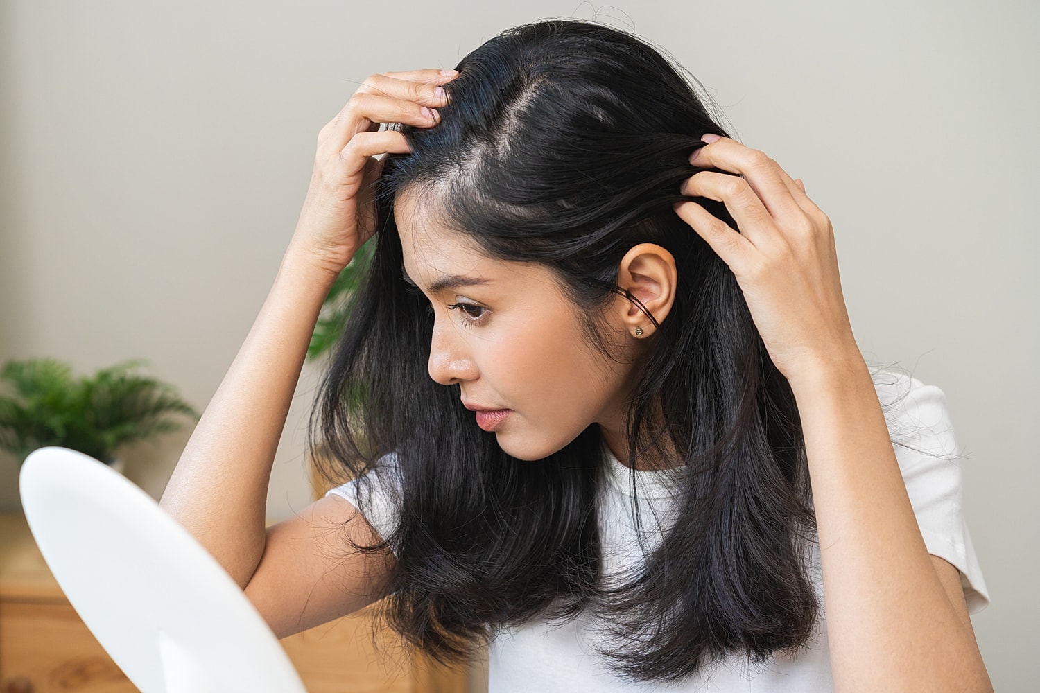 Woman examining her hair in a mirror.