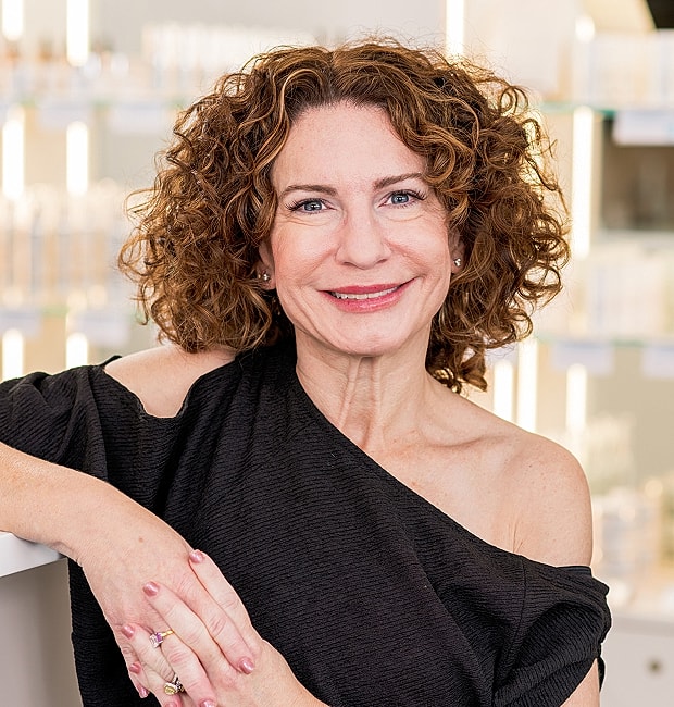 Smiling woman with curly hair in beauty setting.