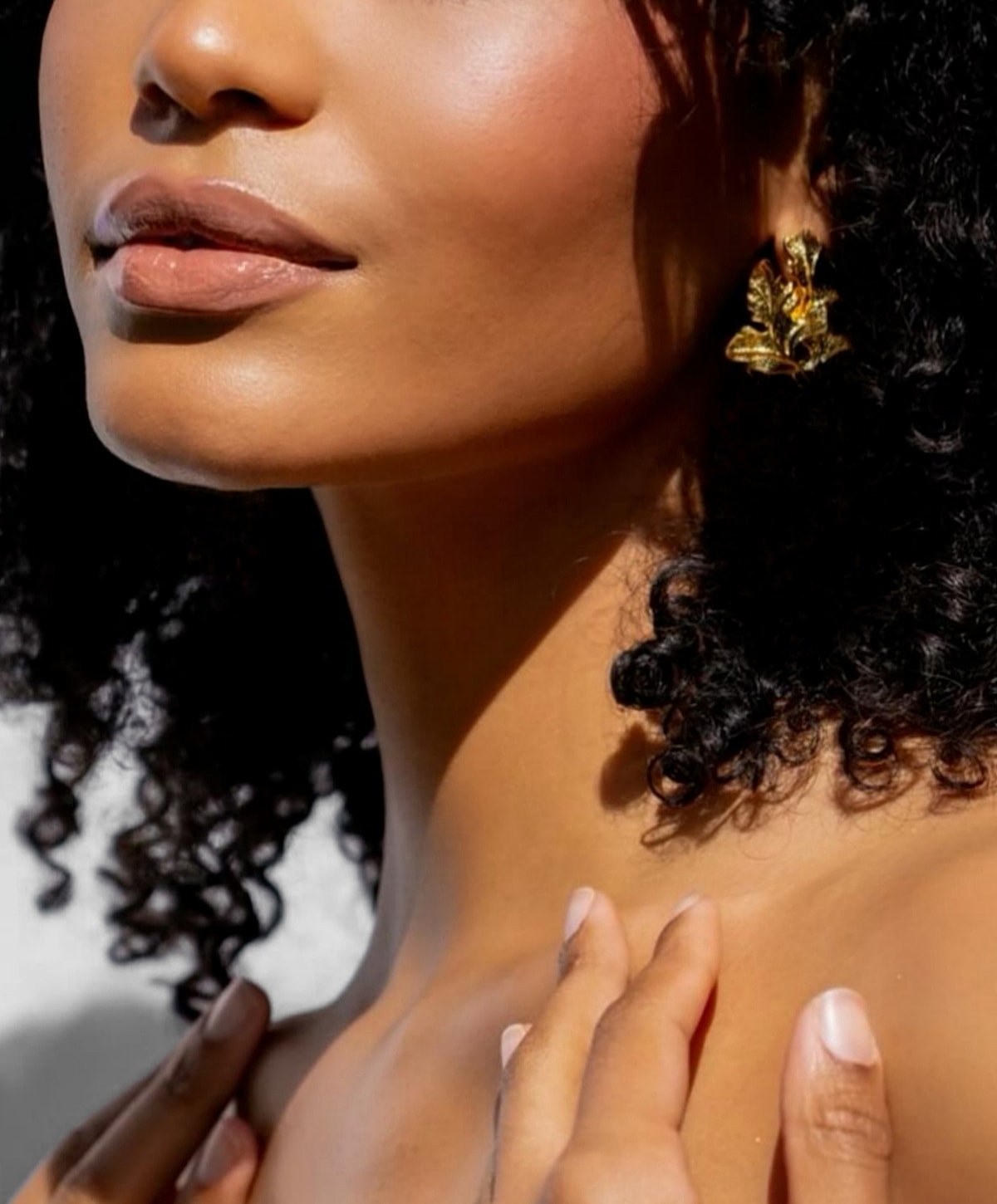 Close-up of woman with curly hair and earrings.