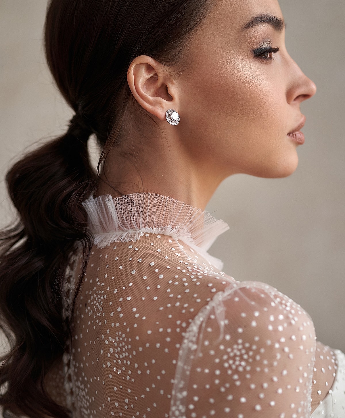Elegant woman in sheer dotted blouse profile view.