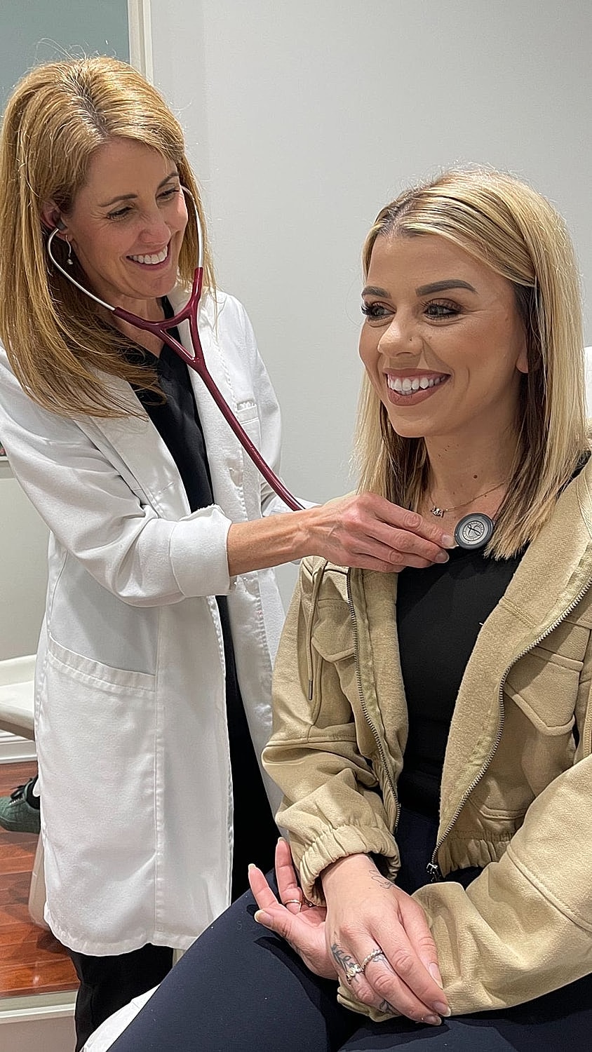 Doctor using stethoscope on smiling patient.