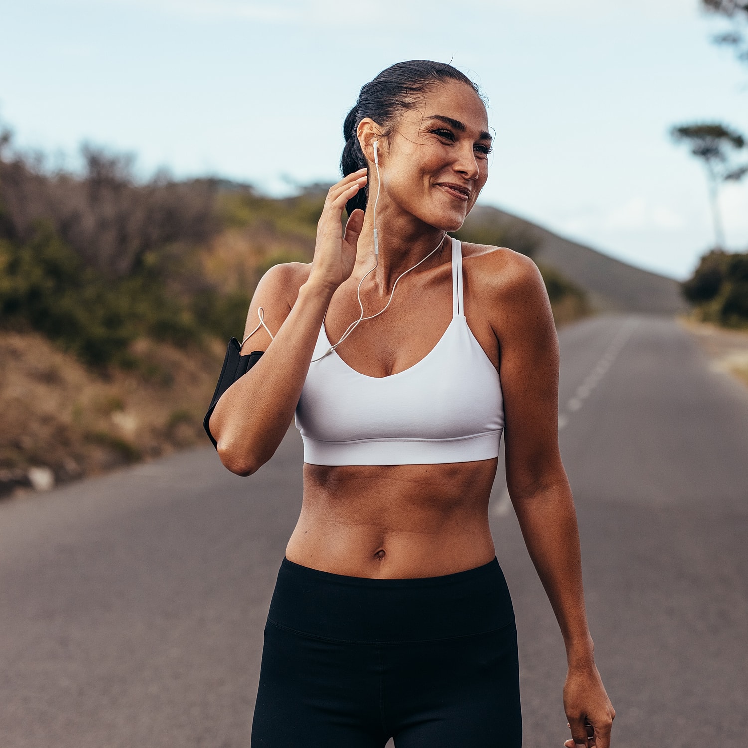 Woman jogging with headphones on a road.