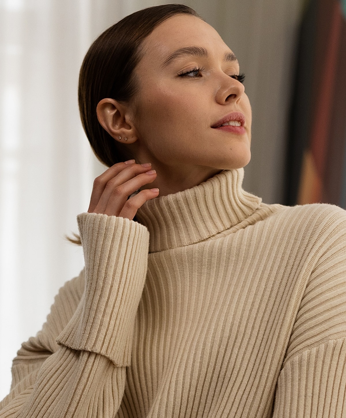 Woman in cozy turtleneck sweater, thoughtful pose.