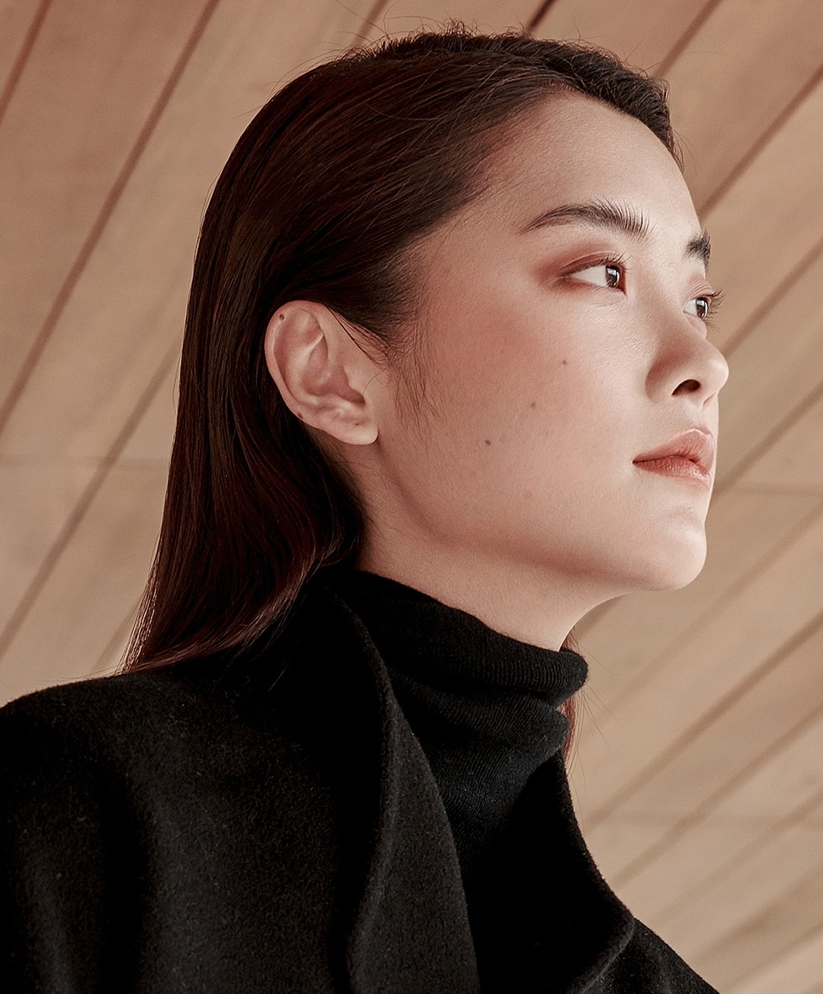 Profile of a woman against wooden background.