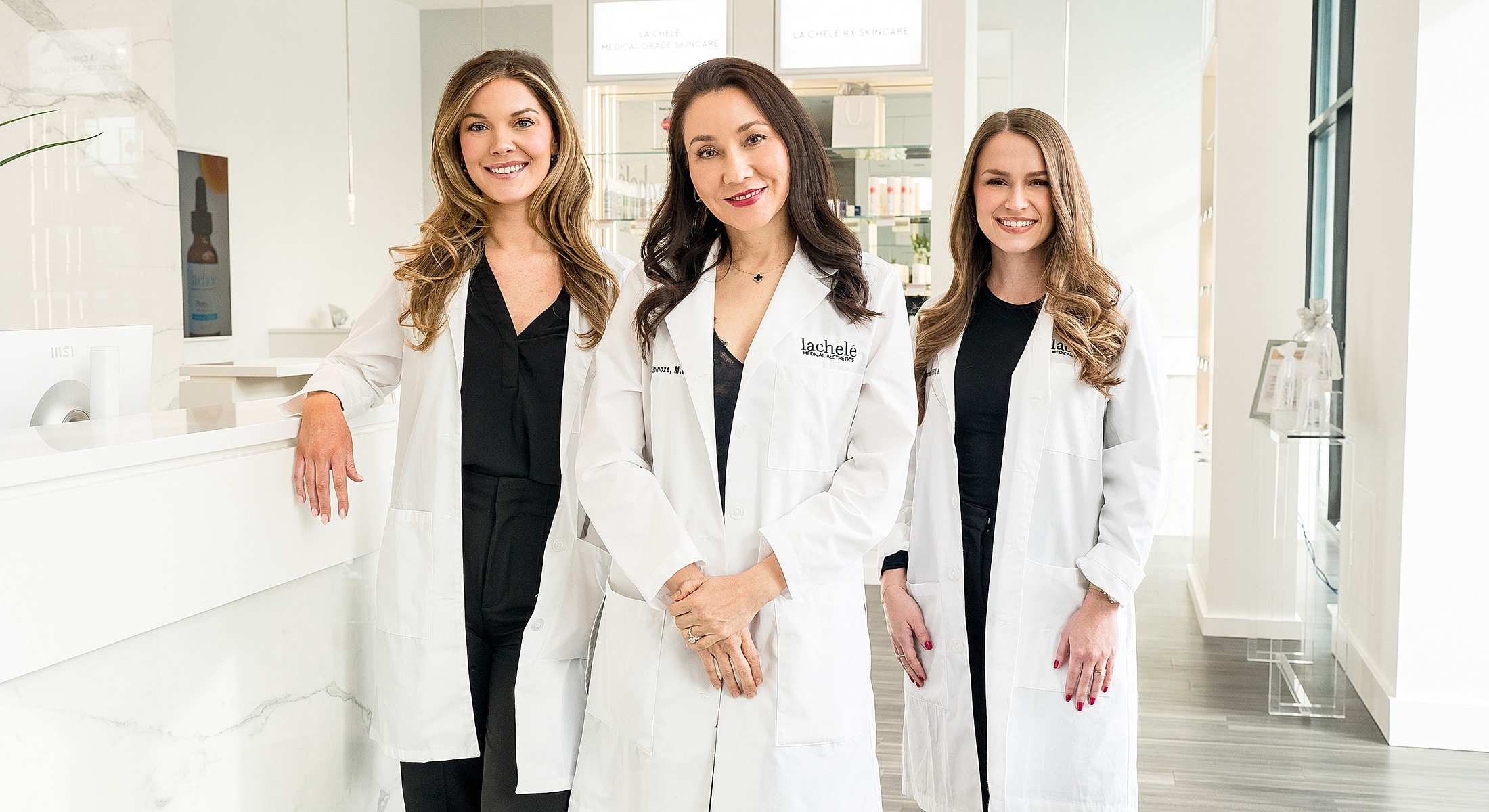 Three professionals in medical lab coats smiling.