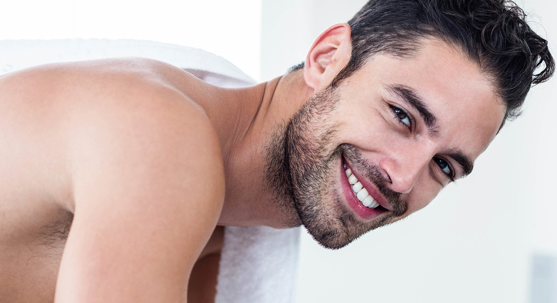 Smiling man wrapped in a towel indoors.