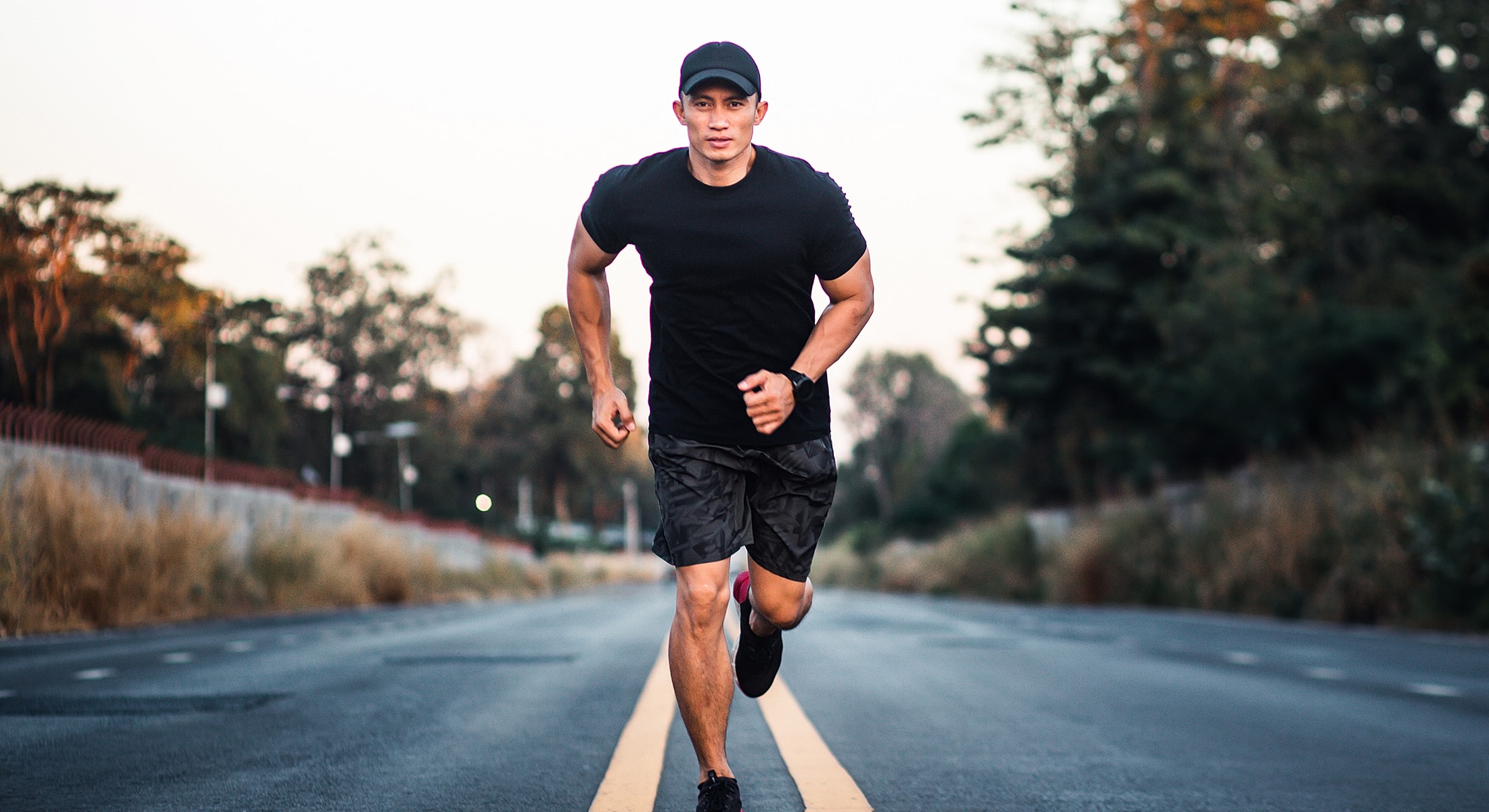 Man running on an empty road at sunset.